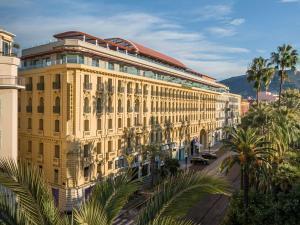 a large yellow building with palm trees and a street at Anantara Plaza Nice Hotel - A Leading Hotel of the World in Nice