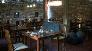 a restaurant with wooden tables and chairs and a stone wall at Wada1 in Aihole