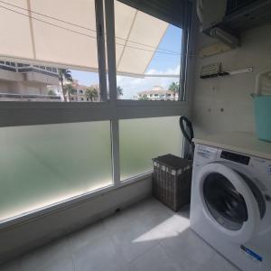 eine Waschküche mit einer Waschmaschine und einem Fenster in der Unterkunft FINALBIR MIMAR- Vistas al mar-Sea view- parking in Albir