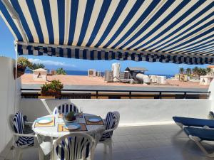 a patio with a table and chairs and a view of the ocean at Arena Sol by HelloApartments in Puerto de Santiago