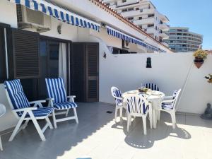 a patio with blue and white chairs and a table at Arena Sol by HelloApartments in Puerto de Santiago
