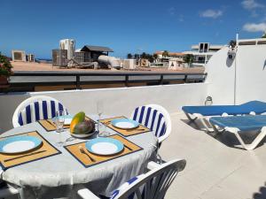 a table and chairs on a patio with a view of the ocean at Arena Sol by HelloApartments in Puerto de Santiago