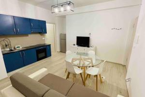 uma sala de estar com uma mesa e uma cozinha com armários azuis em Alba - Parcheggio gratis, fronte caserma e clima em Ascoli Piceno