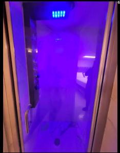 einer Glastür mit einem Spiegelbild einer Person in einem lila Licht in der Unterkunft bassement whit jackuzzi and pool in Copiague