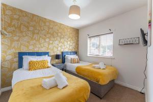 Newly Refurbished Townhouse, Free Parking & Garden في New Bilton: غرفة نوم بسريرين بملاءات صفراء وبيضاء