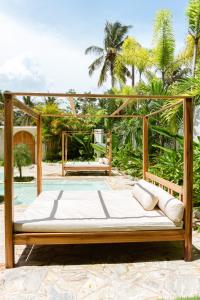 a wooden bed on a patio with palm trees at KALAVA VILLA in Ahangama