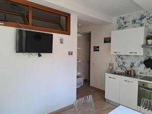 a kitchen with white cabinets and a tv on the wall at Casa Tua in Marina di Campo