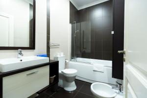La salle de bains est pourvue de toilettes blanches, d'un lavabo et d'une baignoire. dans l'établissement Ola Lisbon - Campo Pequeno, à Lisbonne