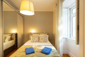ein Schlafzimmer mit einem Bett mit blauen Kissen und einem Spiegel in der Unterkunft Ola Lisbon - Campo Pequeno in Lissabon