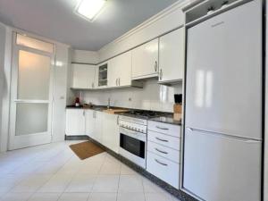 拉科魯尼亞的住宿－Brigantia Coruña，白色的厨房配有白色橱柜和冰箱。