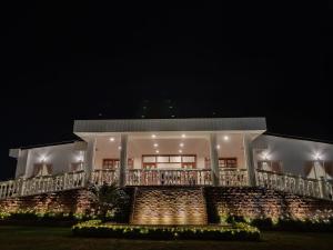 uma grande casa branca com uma varanda à noite em Windermere Hotel em Shillong