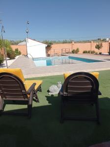 dos sillas sentadas en un césped cerca de una piscina en Huerta Alegría, en Casariche