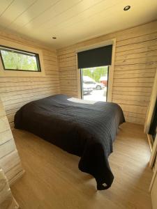 Cama grande en habitación de madera con ventana en Villa Rimminranta, en Sapsalampi