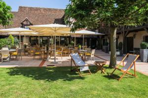 een groep stoelen en tafels met parasols in het gras bij Auberge Du Cheval Blanc - Teritoria in Selles-Saint-Denis