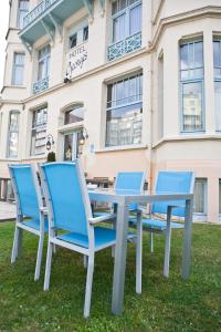 
a row of blue chairs sitting in front of a building at Hotel Georges in Wenduine
