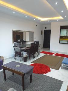 un soggiorno con tavolo, sedie e tappeto rosso di Cozy apartment in El Rehab a Il Cairo