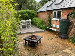 eine Terrasse mit einem Tisch und einer Bank im Hof in der Unterkunft Tiny Cottage for couples in the countryside in Shalfleet