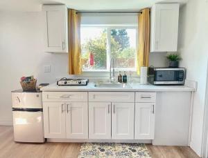 uma cozinha com armários brancos, um lavatório e uma janela em NEW private tiny home near GreenLake/Lightrail/I-5 em Seattle