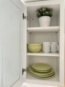 un armario blanco con platos y cuencos y una planta en NEW private tiny home near GreenLake/Lightrail/I-5 en Seattle