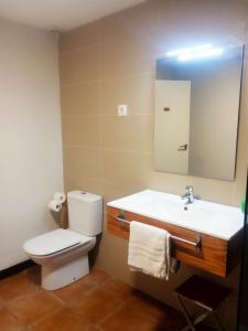 a bathroom with a toilet and a sink and a mirror at El Olivo in Torre del Compte