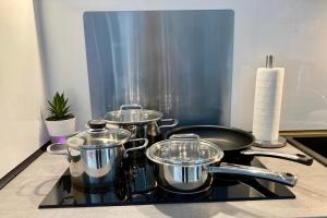 three pots and pans sitting on top of a stove at Living at Saarpartments with 2 Bedrooms, Netflix- Business & Holiday Apartments for Long- and Short term Stay, 3 min to Train-Station and Europa Galerie in Saarbrücken