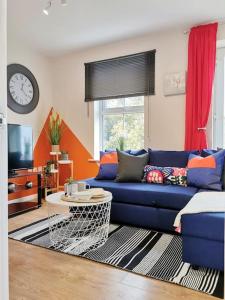a living room with a blue couch and a clock at Fivehill Apartment, Long Stay, 4 Showers, Sleeps 10, Free Parking, in Sheffield