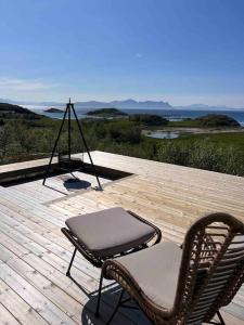 a patio with two chairs on a wooden deck at Sea & Sky Vestfjord Panorama in Lødingen