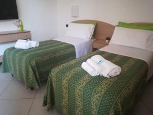 two beds in a hotel room with towels on them at B&B Ninni in Castelbuono