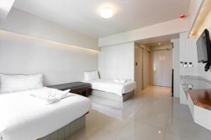 a hotel room with two beds and a television at A Room Bangkok Sathorn in Bangkok