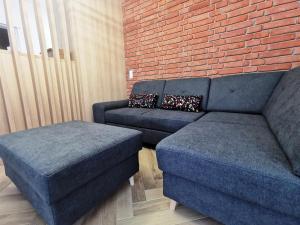 a living room with two blue couches and a brick wall at Apartament na Irysowej in Dobrzeń Wielki