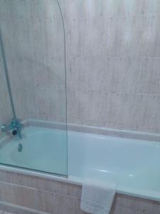 eine Glasduschkabine mit einer Badewanne und einem Handtuch in der Unterkunft Las torres Alquilevante in Benidorm