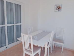 einen weißen Tisch und Stühle in einem Zimmer mit Fenstern in der Unterkunft Las torres Alquilevante in Benidorm