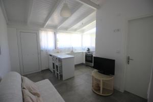 a white kitchen with a couch and a tv in a room at Brand new house with garden, next to the beach in Áyios Ilías