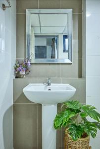 baño con lavabo, espejo y planta en The Trust Ville en Bangkok