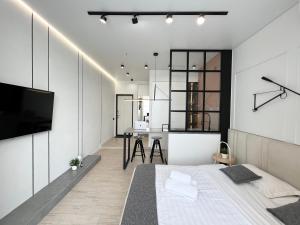 a bedroom with a bed and a tv and a table at Квартира Smart в новом доме in Pavlodar
