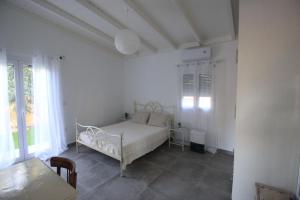 a white bedroom with a bed and a table at Brand new house with garden, next to the beach in Áyios Ilías