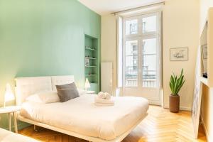 ein Schlafzimmer mit einem weißen Bett und einem Fenster in der Unterkunft Le Crébillon - Splendide appartement de 204m2 in Nantes