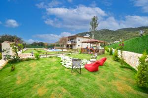 a yard with red chairs and a house at KYANEAİ VİLLA in Demre