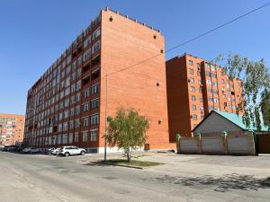 a large brick building with cars parked in front of it at Апартаменты SMART №4 in Pavlodar