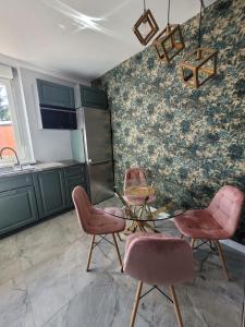 a kitchen with pink chairs and a glass table at Lupus Apartamenty in Poznań