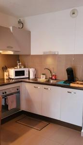 a kitchen with white cabinets and a microwave at T2 pic de l’ours Fontromeu in Font-Romeu