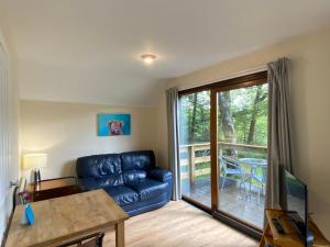 a living room with a couch and a sliding glass door at Burnbank Lodges in Spean Bridge