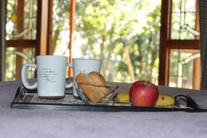 twee koffiemokken en een appel op een dienblad bij THE ORCHID GUESTHOUSE 
