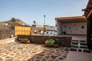 a building with a stone wall and some potted plants at Casa Tilama in Tinajo