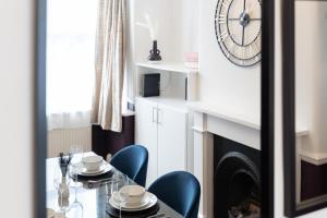 ein Esszimmer mit Tisch und Stühlen und einer Uhr in der Unterkunft Watford Casa - 2 bed and 2 bath home near Watford Junction Station in Watford