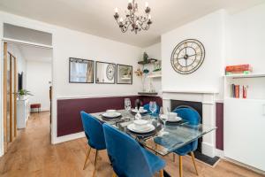 ein Esszimmer mit einem Glastisch und blauen Stühlen in der Unterkunft Watford Casa - 2 bed and 2 bath home near Watford Junction Station in Watford