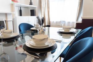 ein Glastisch mit Stühlen und Tellern und Weingläsern in der Unterkunft Watford Casa - 2 bed and 2 bath home near Watford Junction Station in Watford