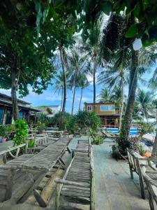 una fila di panchine di legno su una spiaggia con palme di Phú Huy Homestay a Phu Quoc