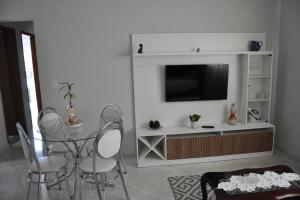 sala de estar con mesa, sillas y TV en Apto com 3 quartos,1 vaga garagem e quintal en Poços de Caldas