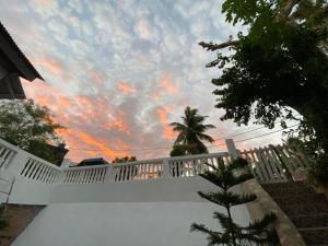 einen weißen Zaun mit wolkigem Himmel im Hintergrund in der Unterkunft Hibiscus Home Stay & Boutique in Port Blair